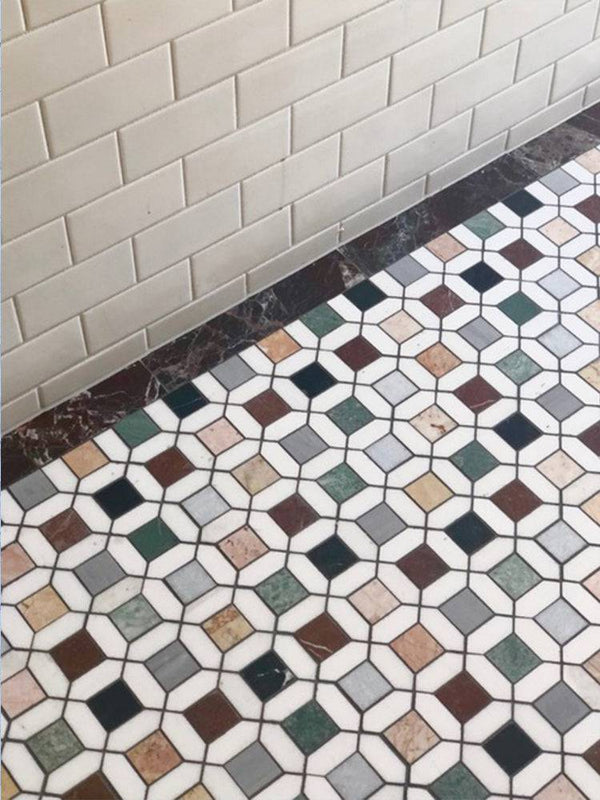 Installed Barcelona Marble Mosaic flooring with multicolour marble squares and white borders, set against cream subway wall tiles and a dark marble skirting.