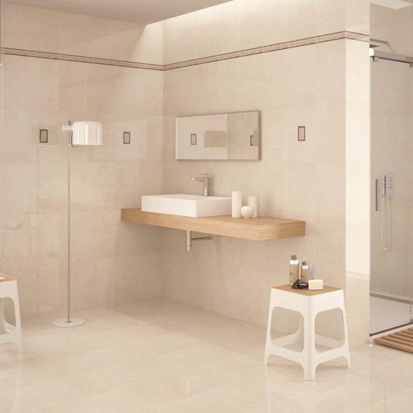 a bathroom with floor-to-ceiling tiling of beige natural stone. there is a short white stool with toiletries on it.