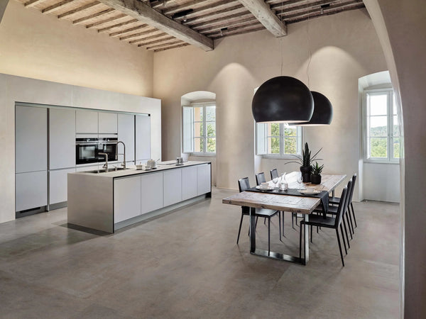 open space kitchen with cement-look porcelain tiles on the floor and large black lamps