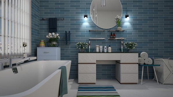 a bathroom with a blue walls, grey flooring tiles and a white bathtub